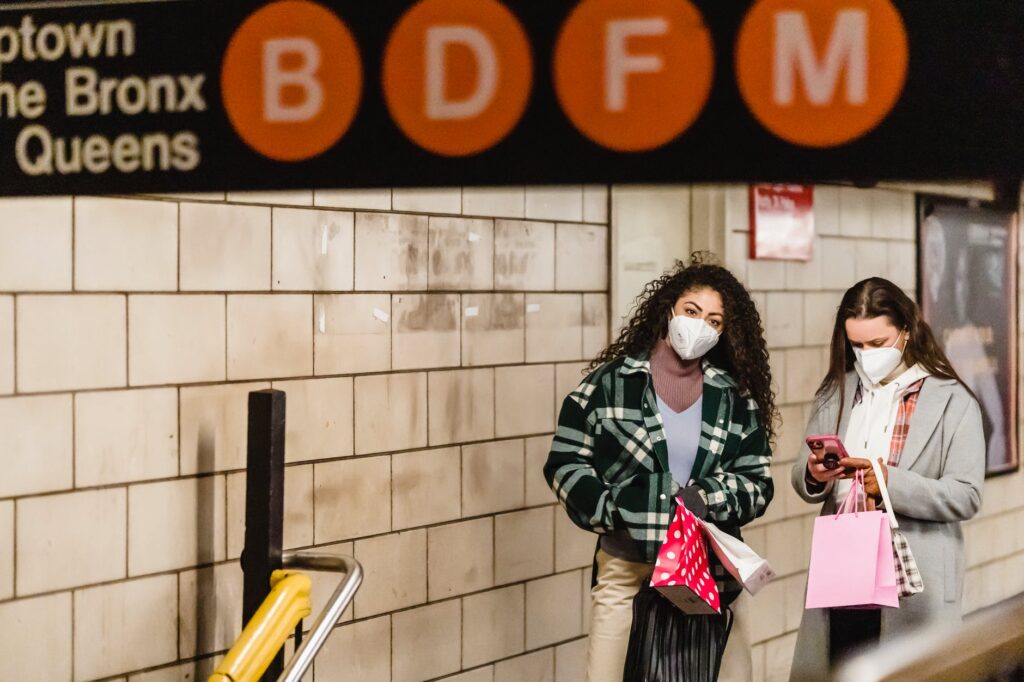 women friends in masks standing in subway passage